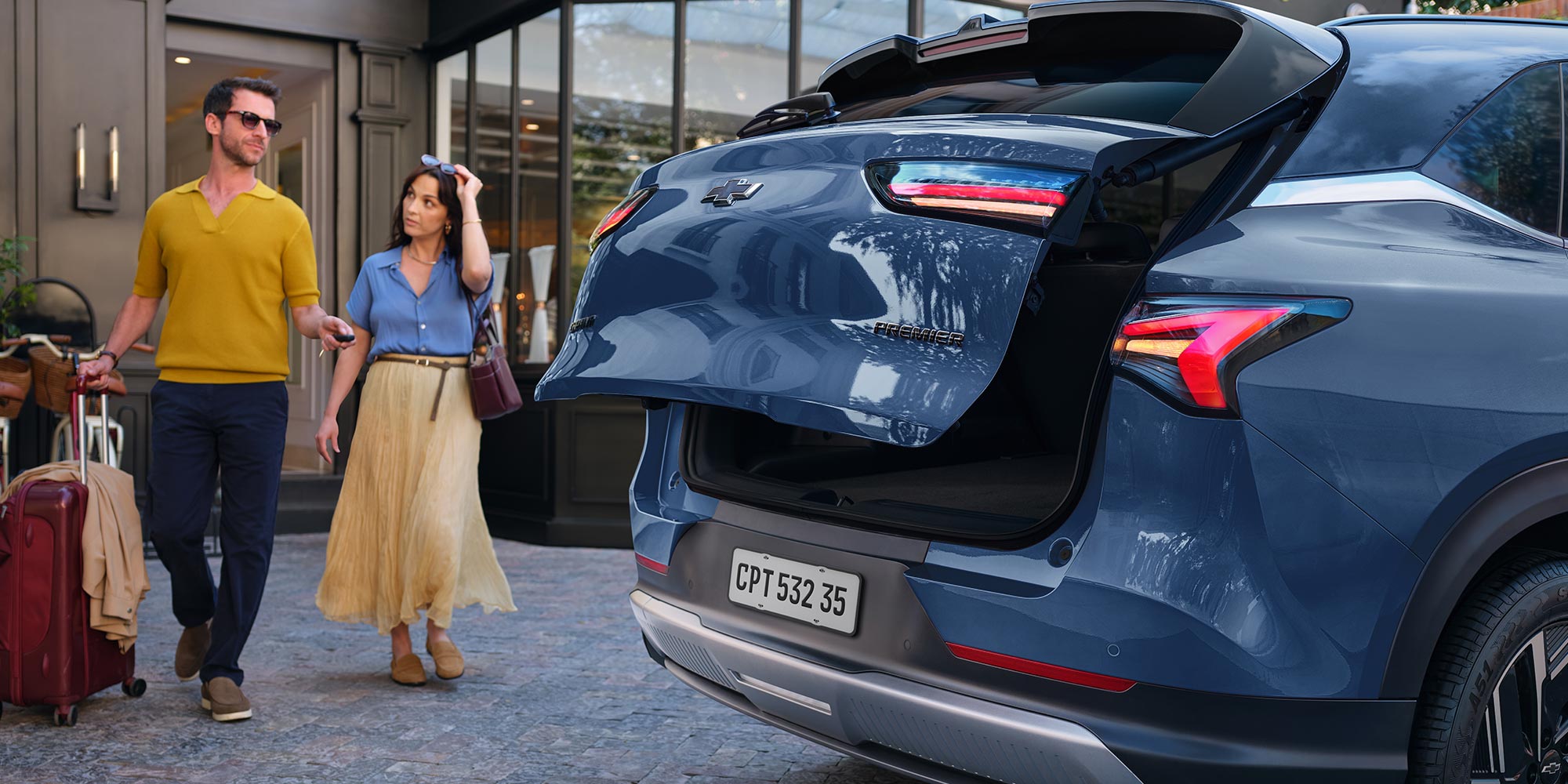 Pareja caminando junto a Chevrolet Captiva híbrida con baúl abierto